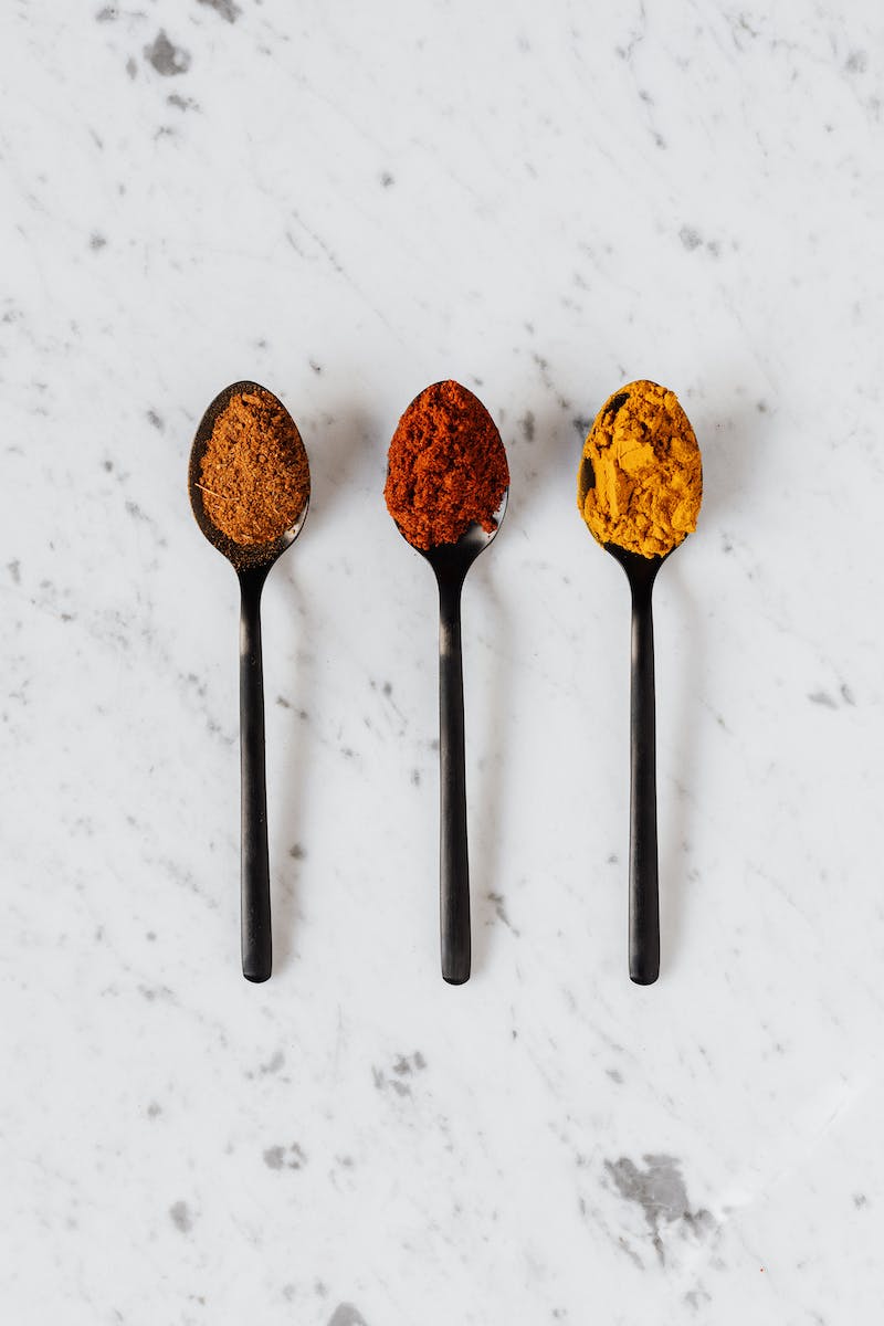 Assorted multicolored dry spices on spoons on table
