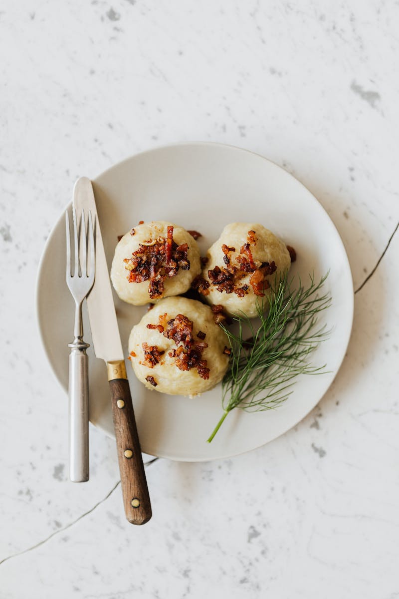 Delicious potato dumplings with fried bacon slices on round plate