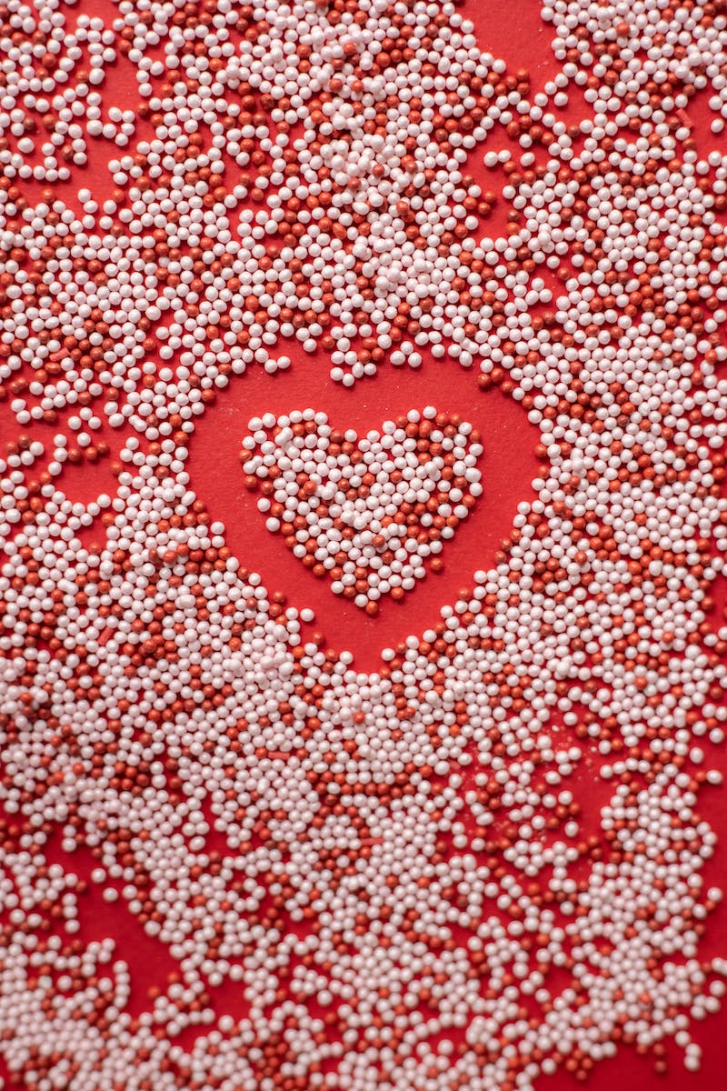 Top view of heart shape in scatter sprinkling on red background for Valentine day