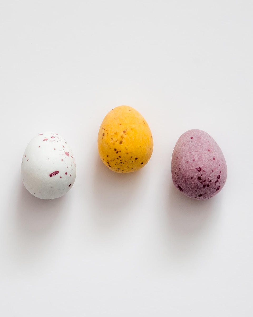 three different colored eggs sitting next to each other