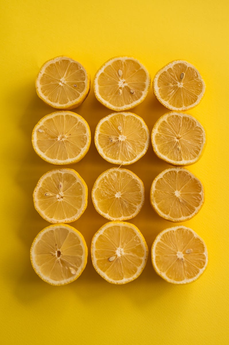From above composition of juicy bright yellow sliced lemons arranged in row on yellow background
