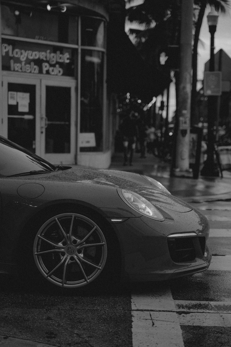 grayscale photo of car parked near building