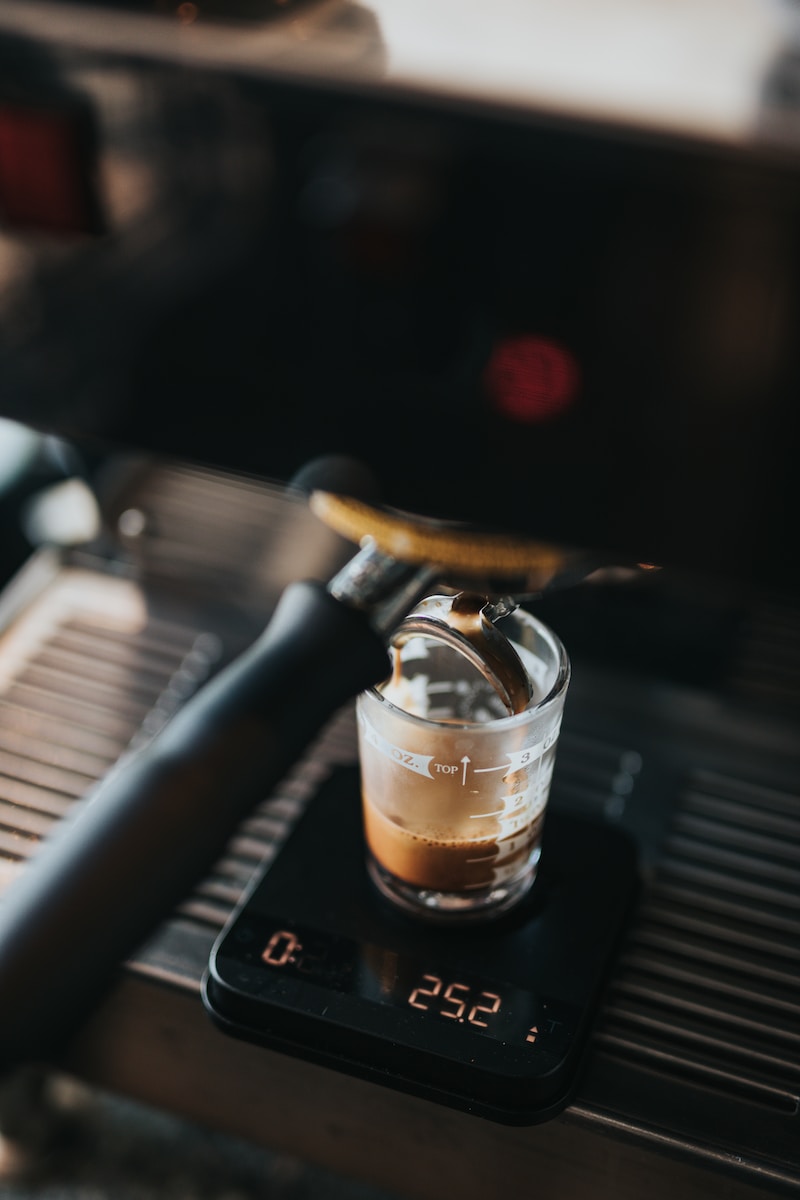 closeup photo of black espresso maker filing clear glass cup