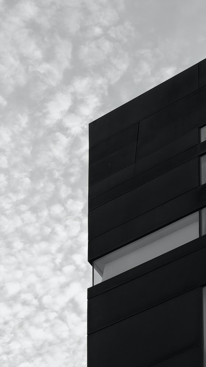 black and white concrete building under white clouds during daytime