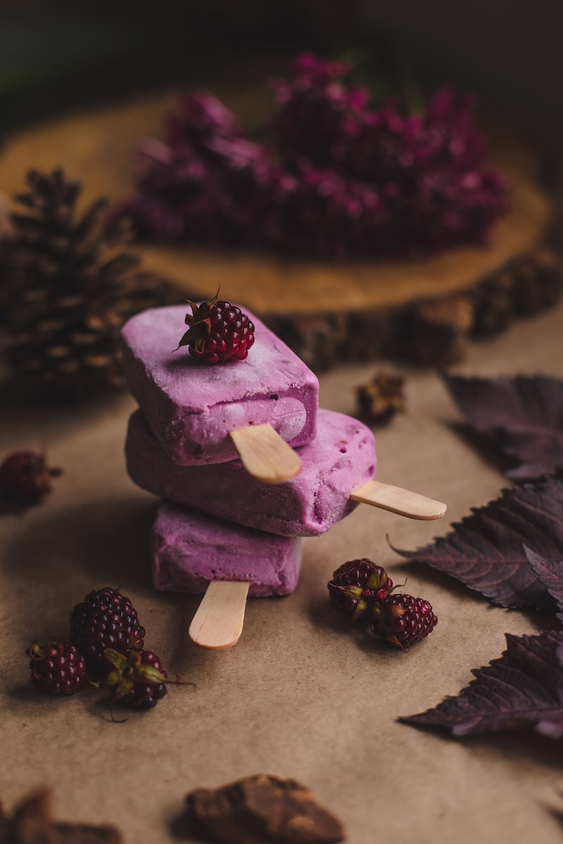 selective focus photography of thee purple ice pops near pine cones
