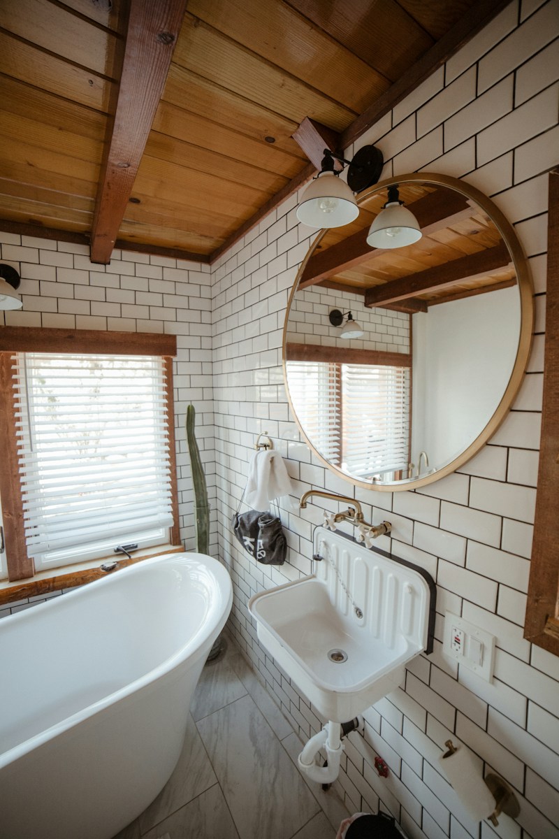 a white bath tub sitting under a bathroom mirror