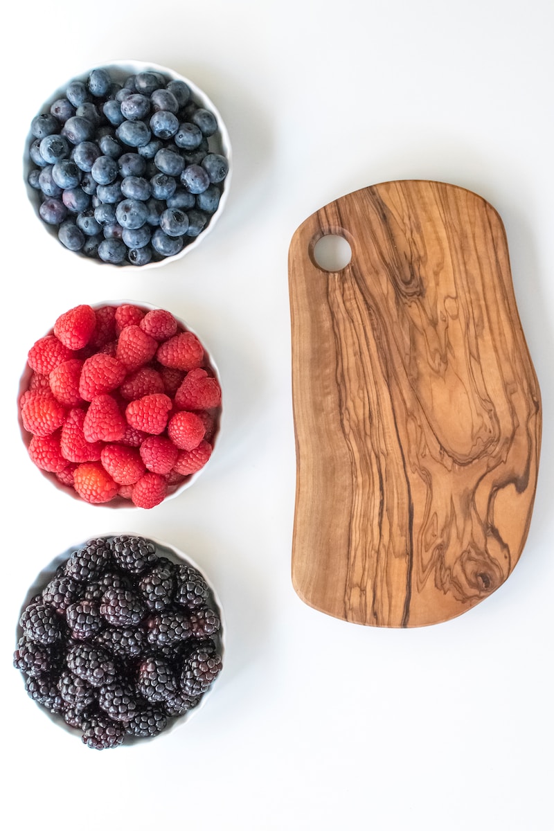 red and black berries on brown wooden chopping board