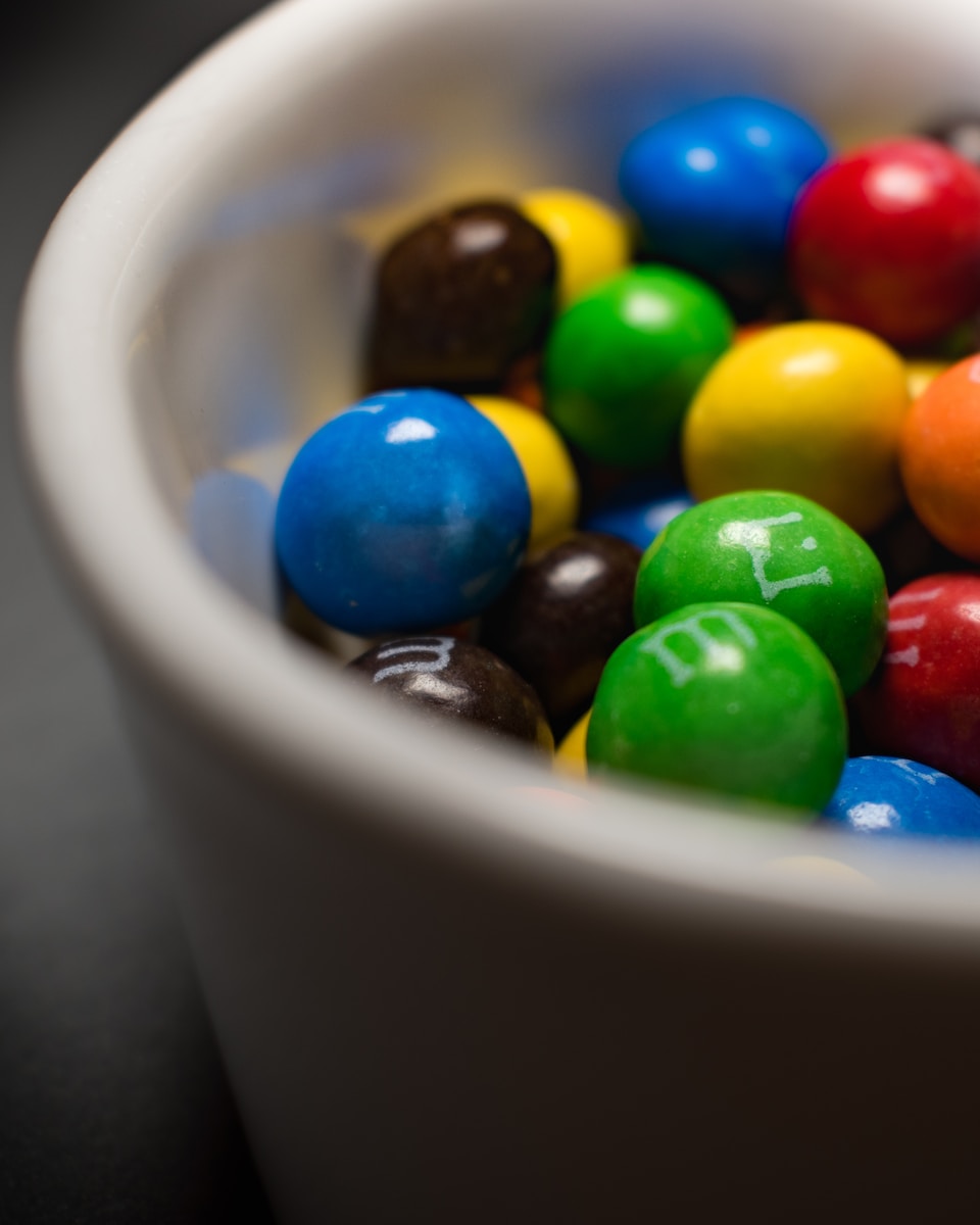 a white bowl filled with lots of colorful candy