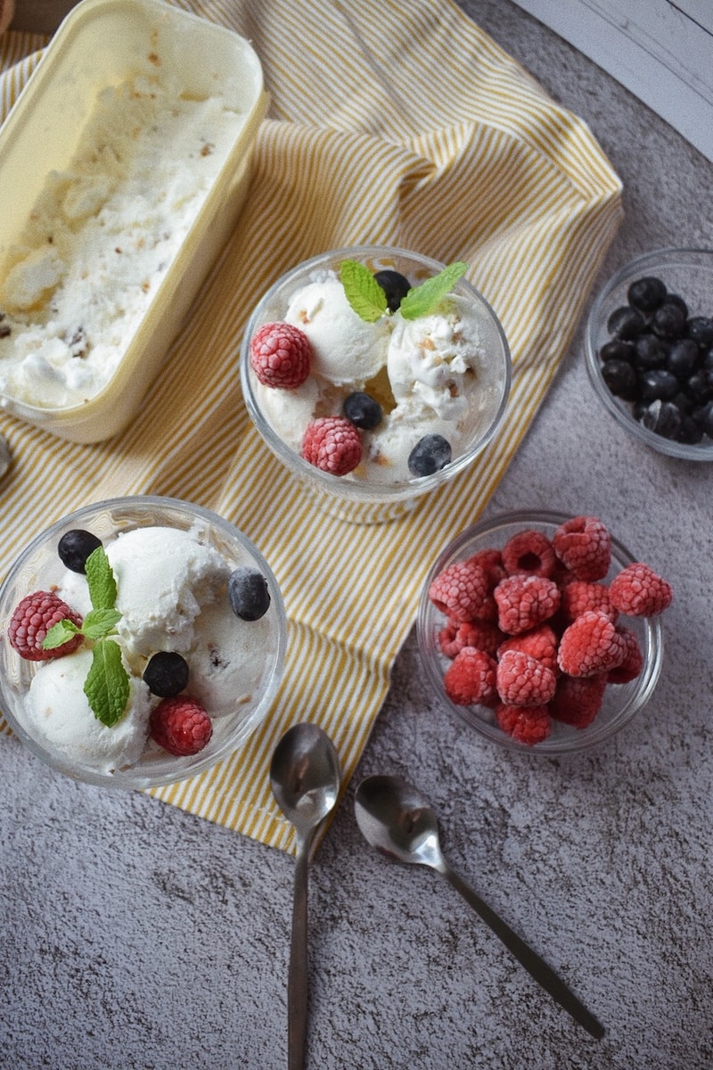 white ice cream with strawberries and blueberries on brown wooden tray