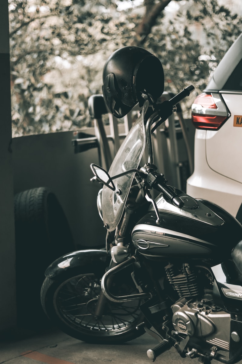 grayscale photo of motorcycle parked beside car