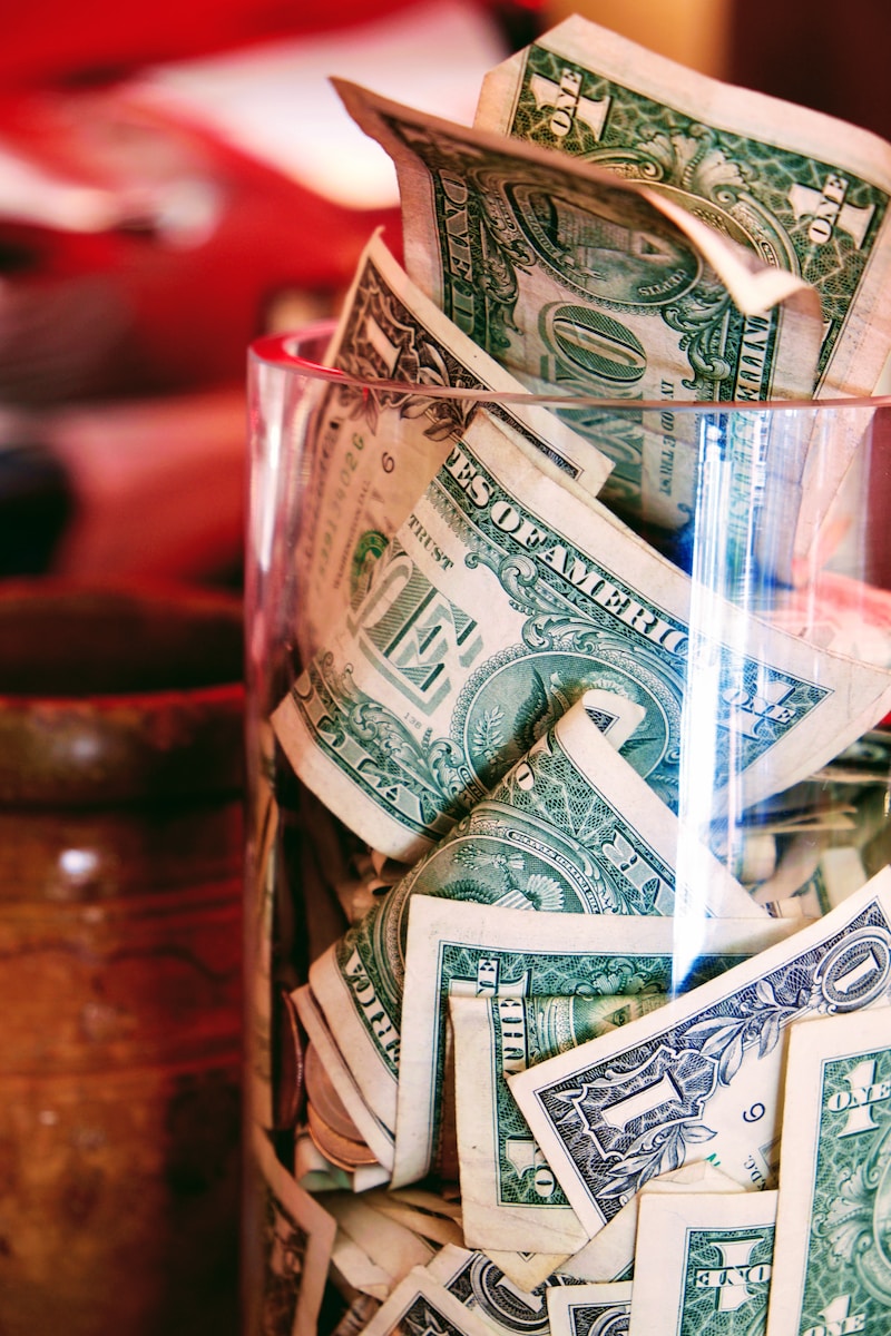 a glass filled with lots of money sitting on top of a table