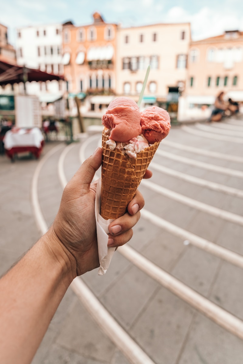 person holding cone of ice cream during daytime