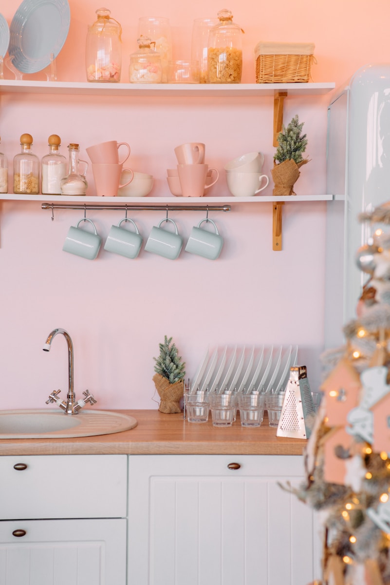 a kitchen with pink walls and white cabinets