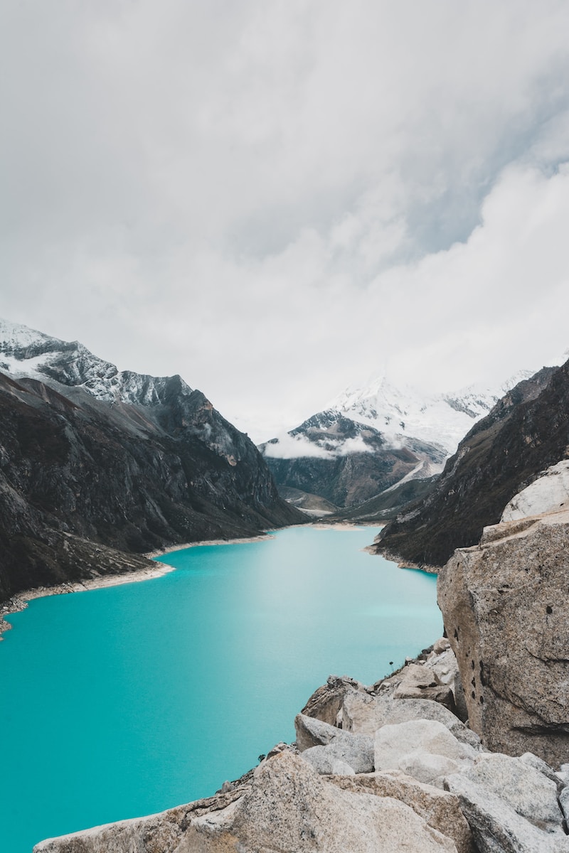 blue lake between mountains under white clouds and blue sky during daytime