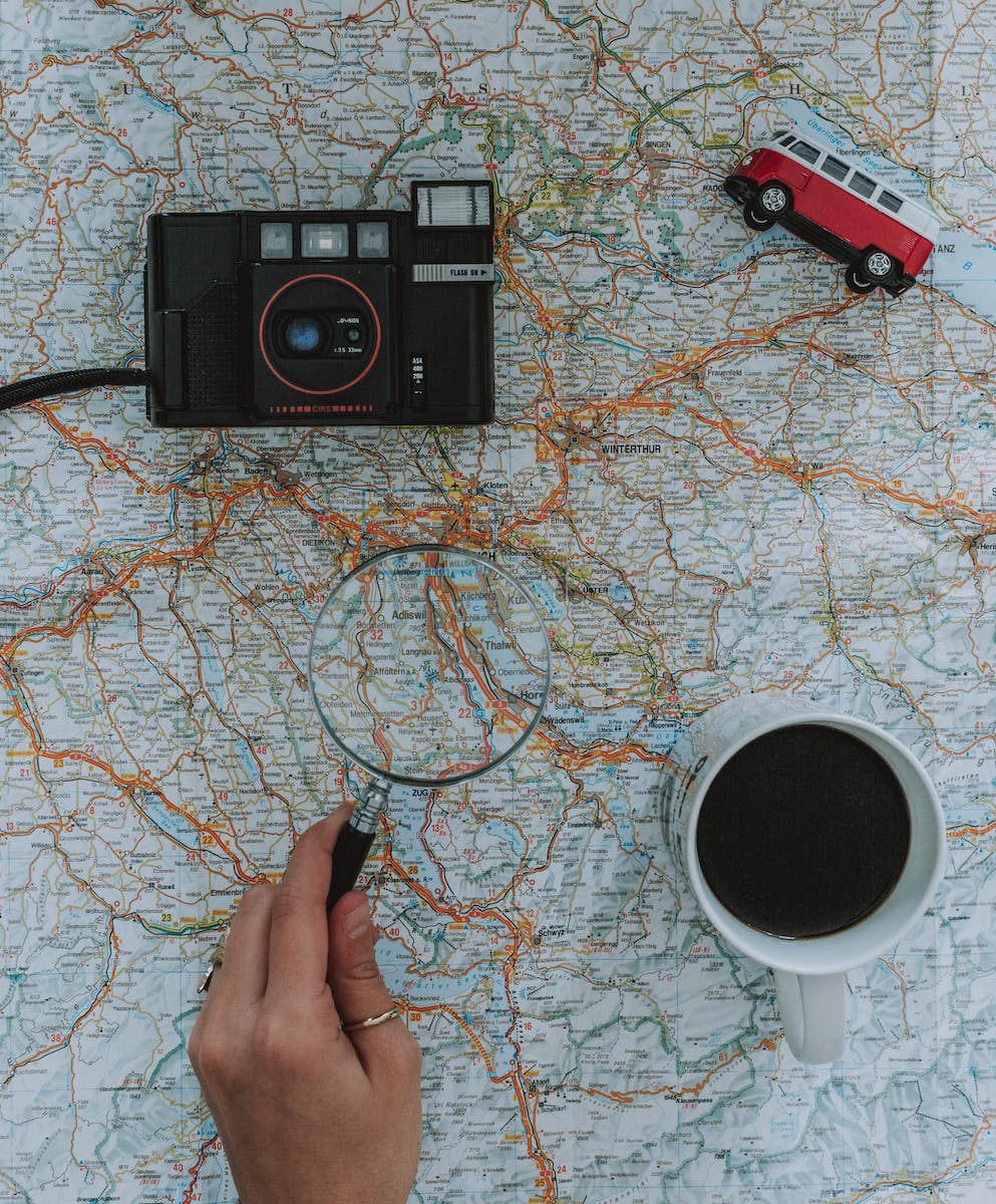 Person Using Magnifying Glass On A Map