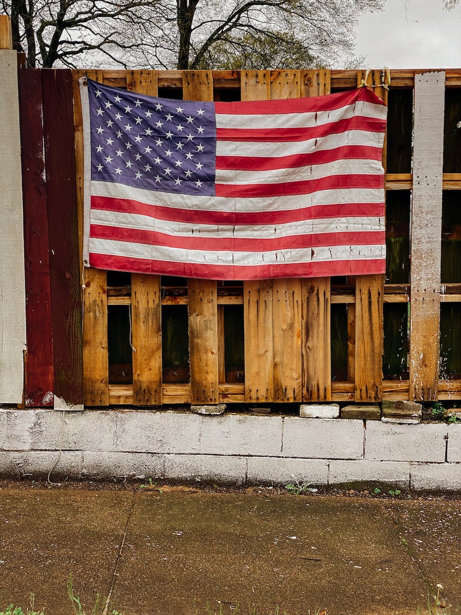 American Flag Hanging On Wooden Fence