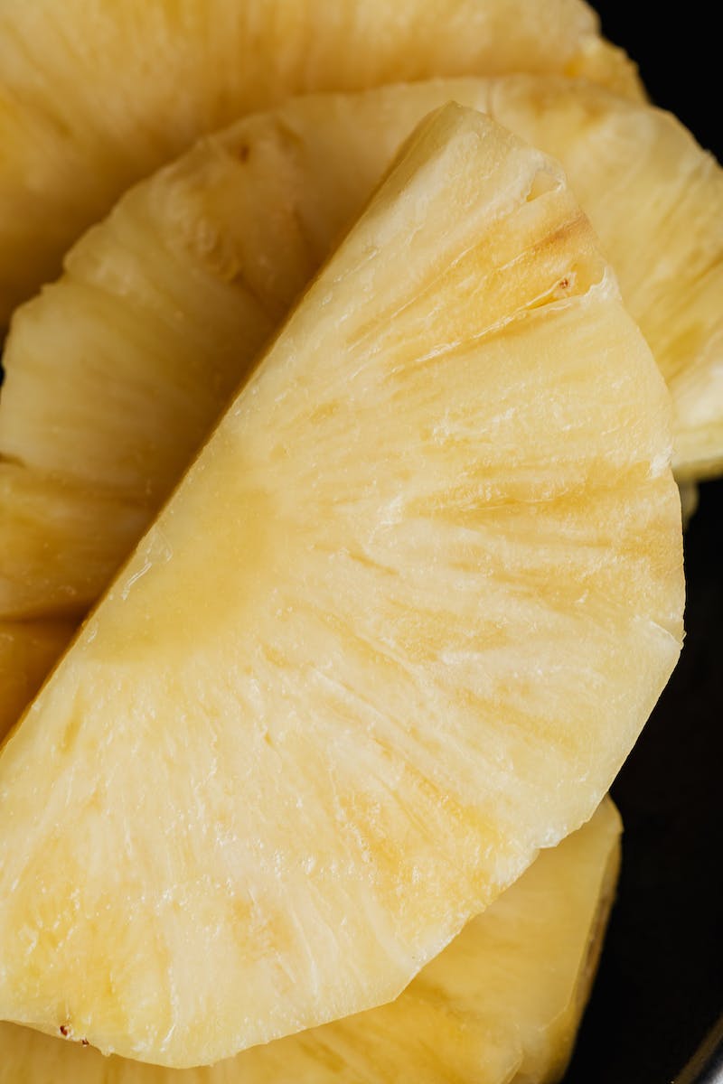 Fresh pineapple pieces on black surface