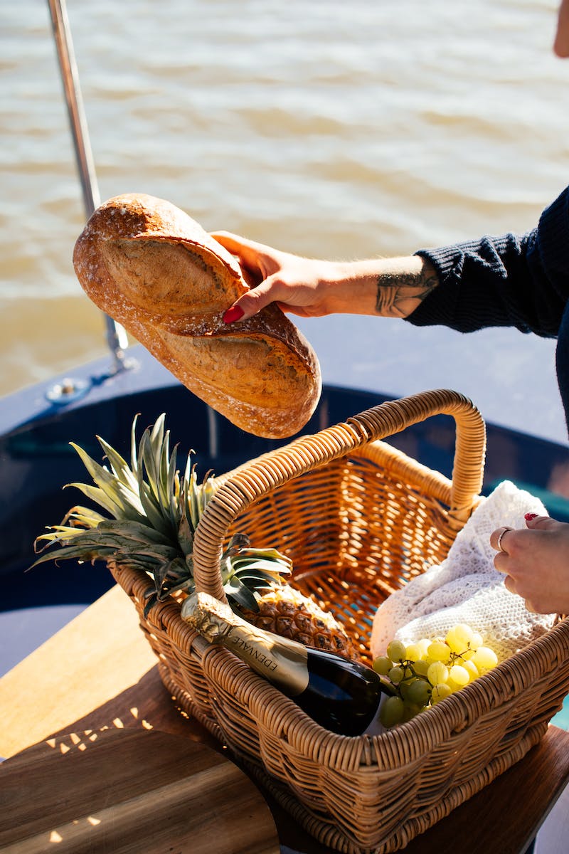 Crop woman with basket of food on yacht