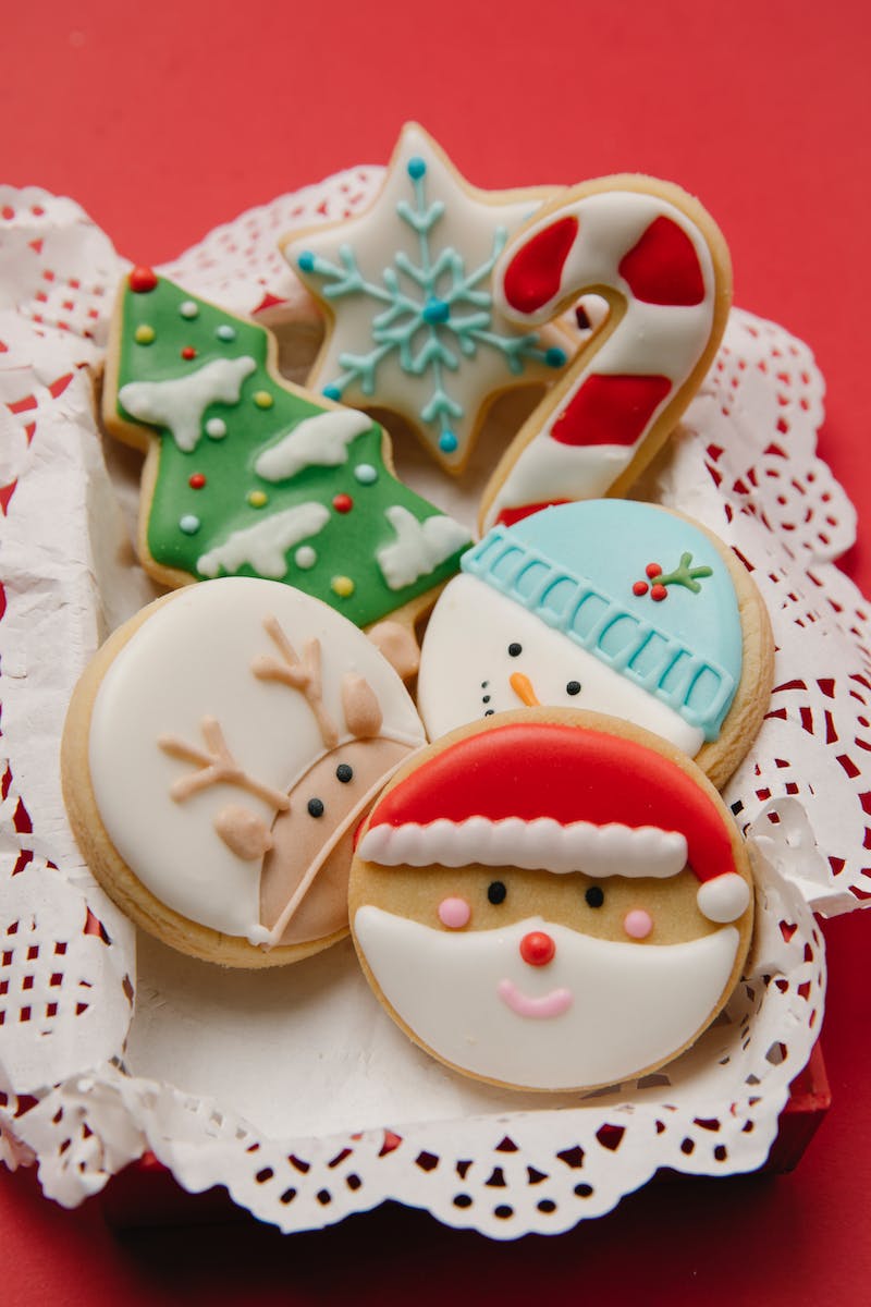 Composition of small box with colourful cookies on white lacy doily on red background