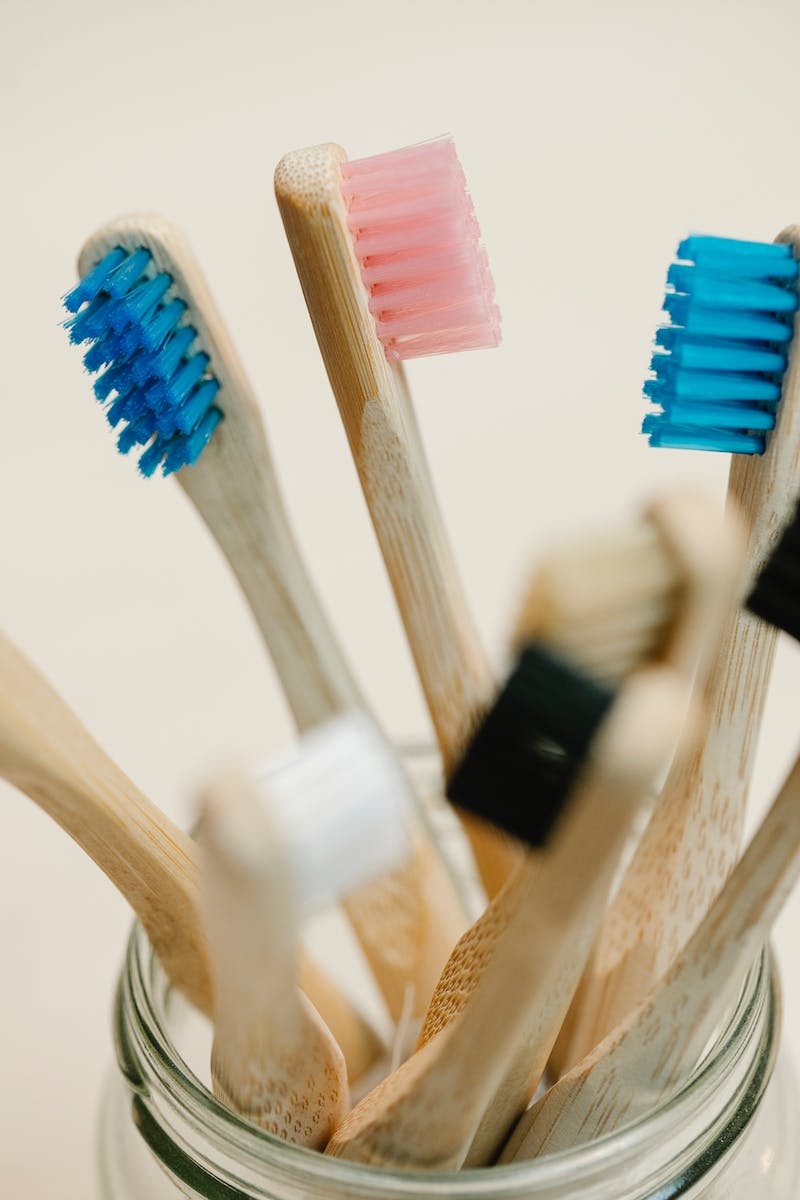 Closeup of colorful toothbrushes made of wood placed in glass jar on white background in daytime