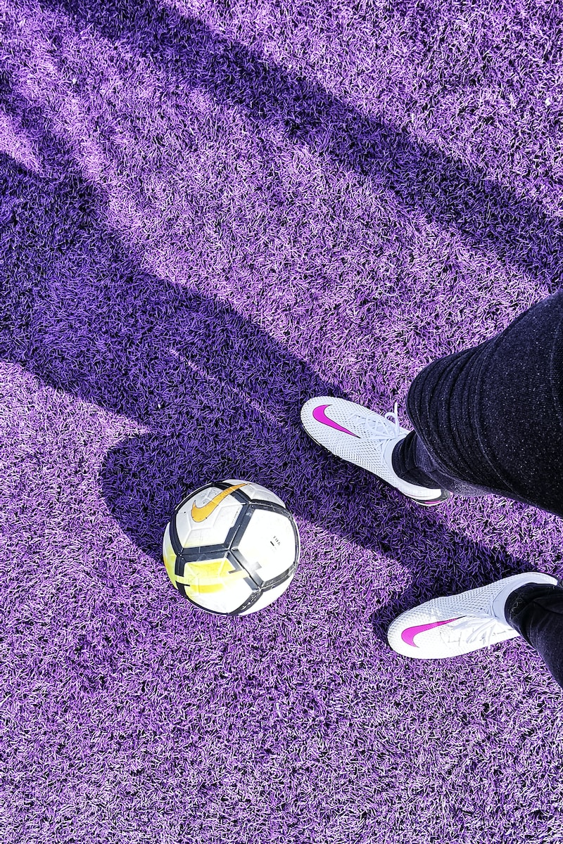 a person's feet with a ball on a purple carpet