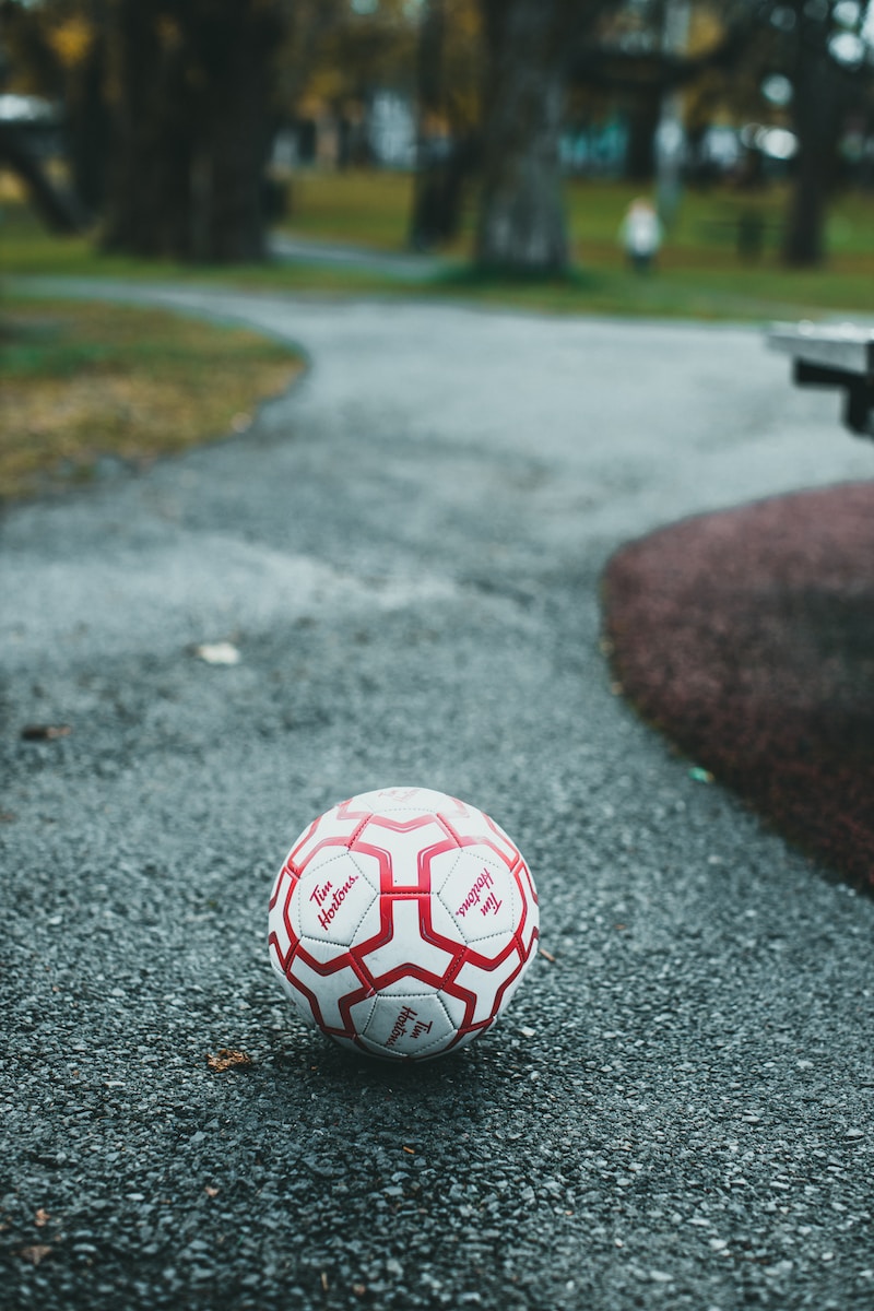 a red and white soccer ball sitting on the side of a road