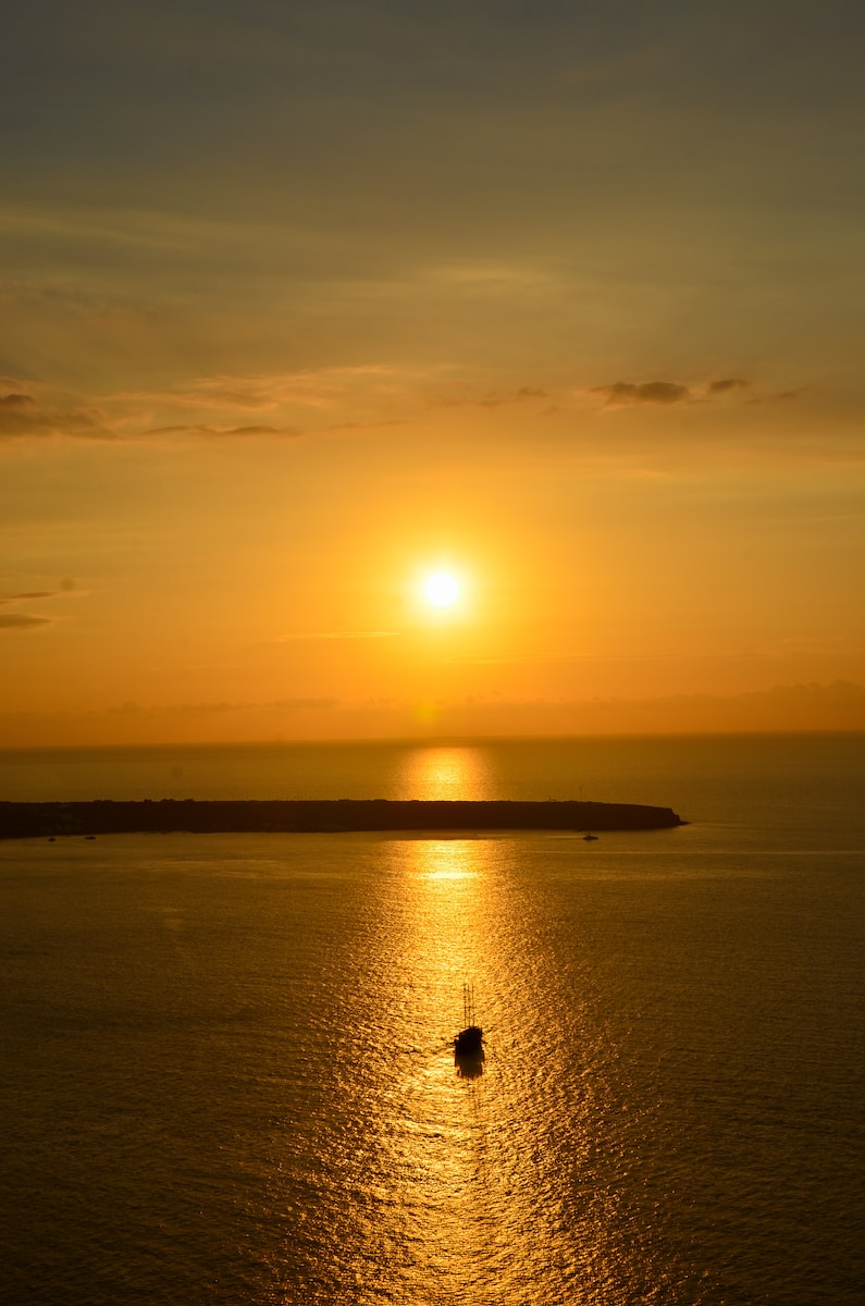 silhouette of person standing on seashore during sunset