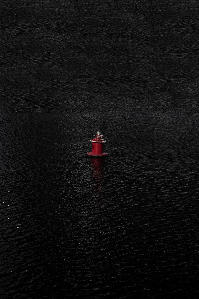 red and black lighthouse on body of water during daytime