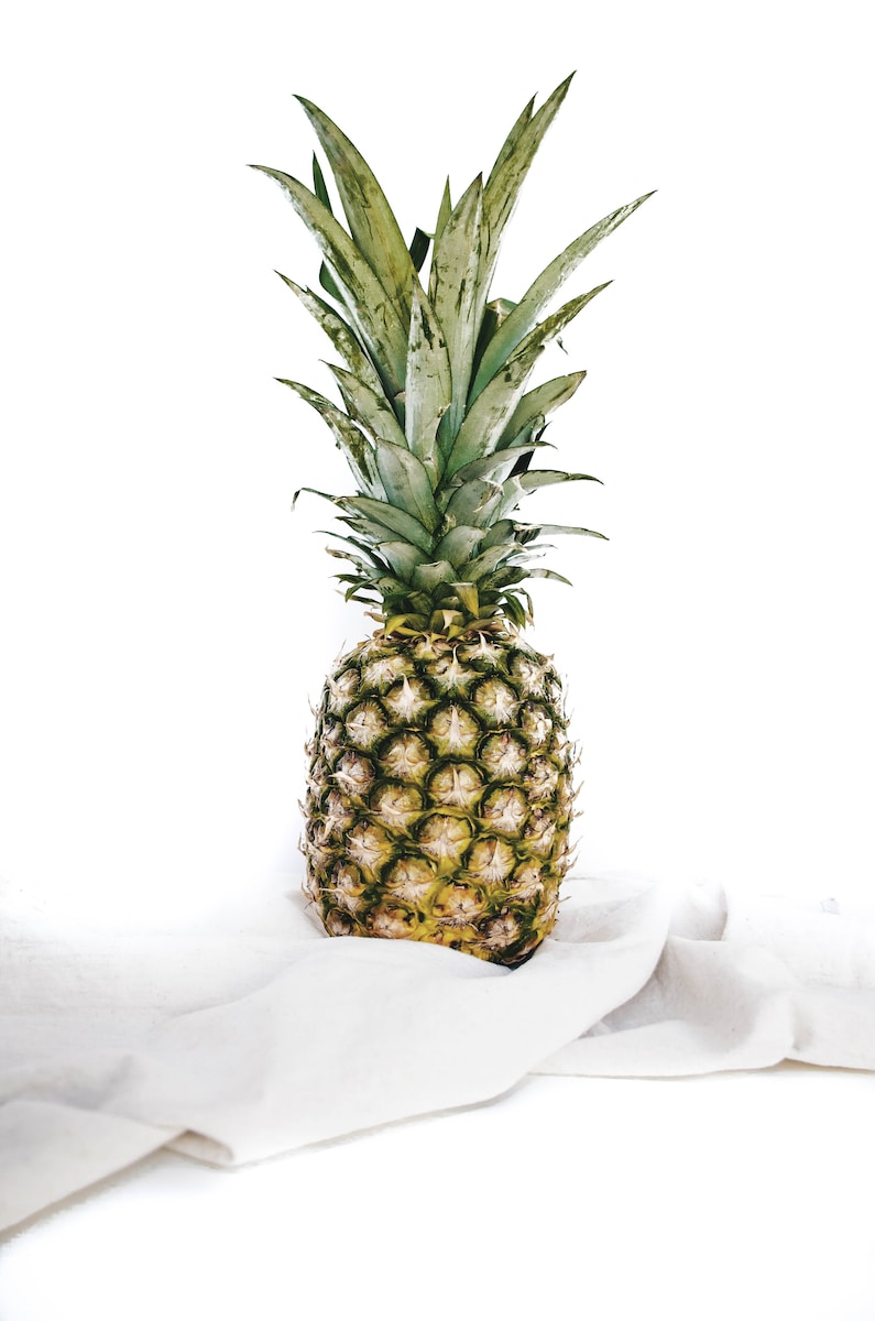 yellow and green pineapple fruit on white textile